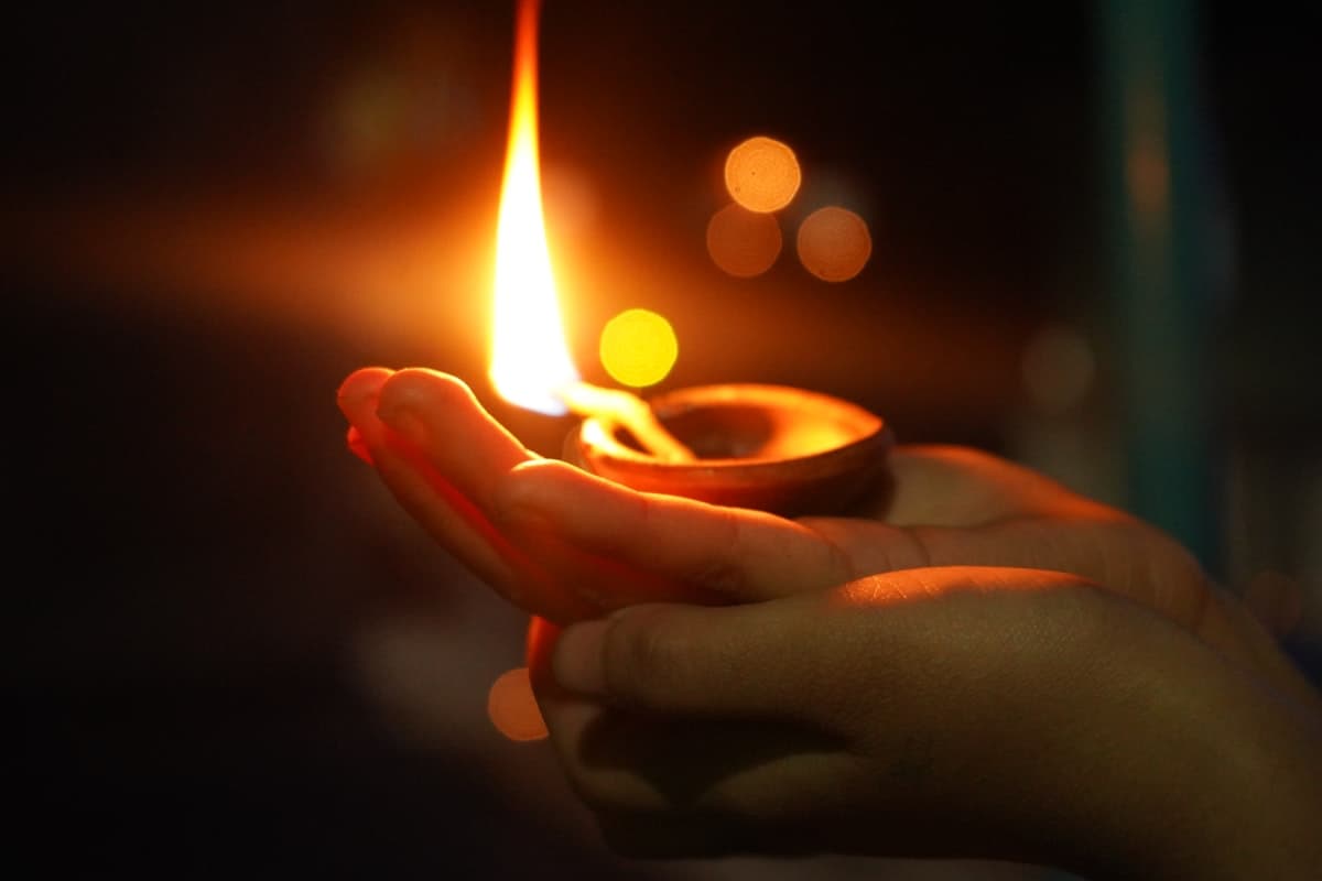 Person holding a lit candle during Tihar
