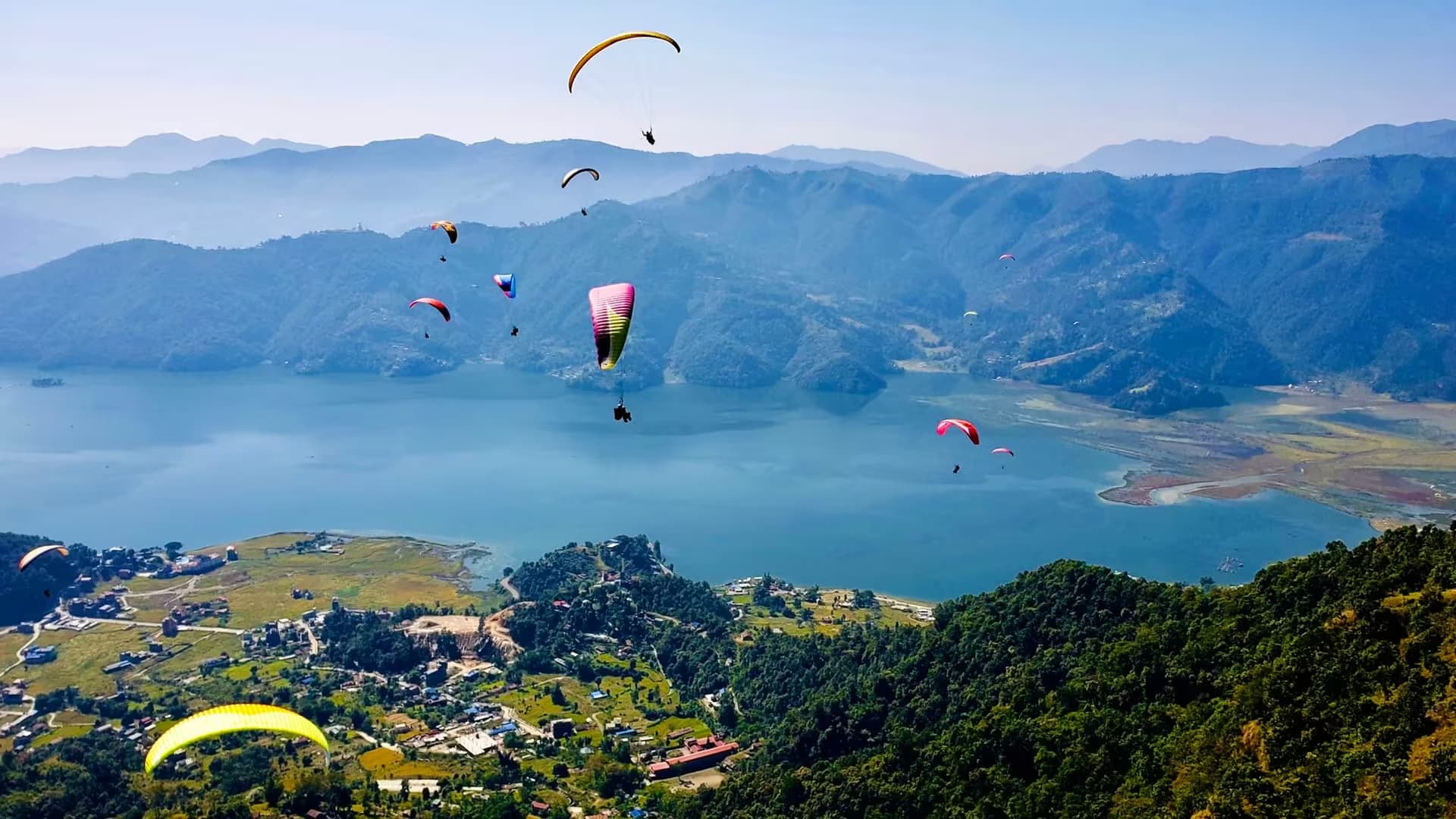 Paragliders soaring over Phewa Lake and green hills