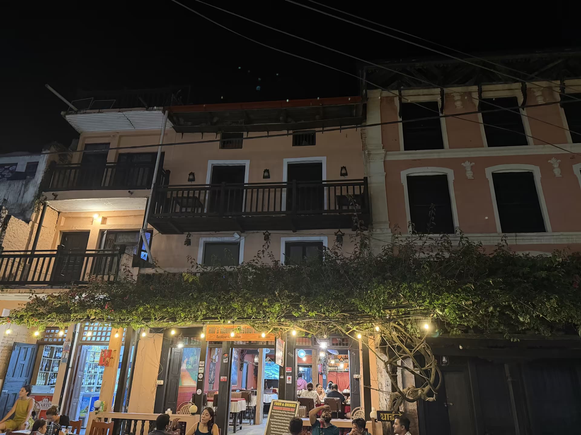 Lamp-lit heritage buildings and a street café in Bandipur at night