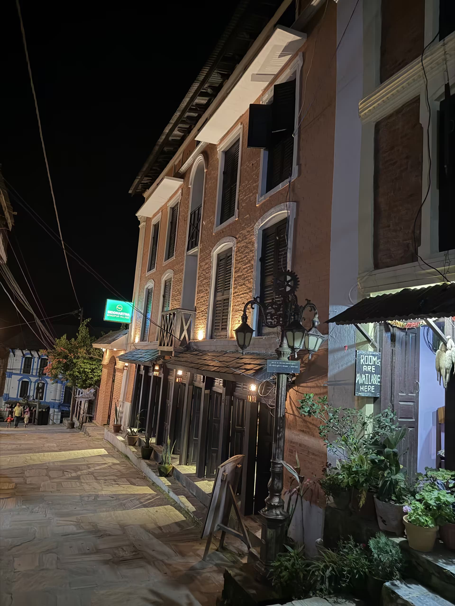 Restored brick building and wrought-iron lamp post on a Bandipur lane at night