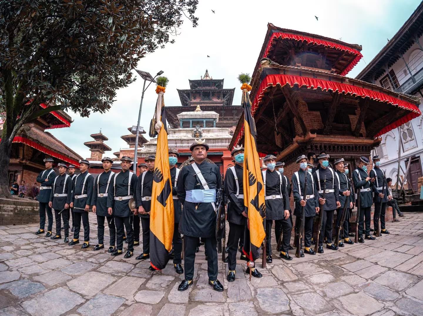 Nepal Army guards in black uniform standing with regimental colours before the temples of Kathmandu Durbar Square