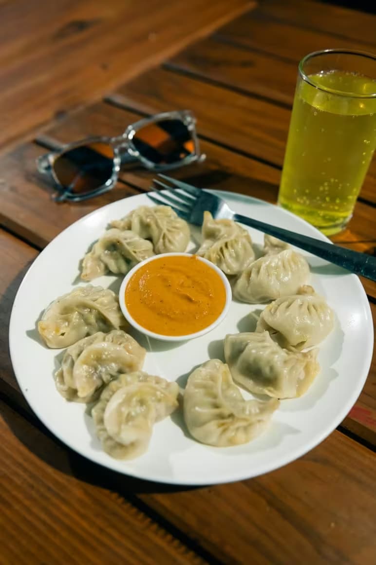 Plate of steamed momos with tomato chutney